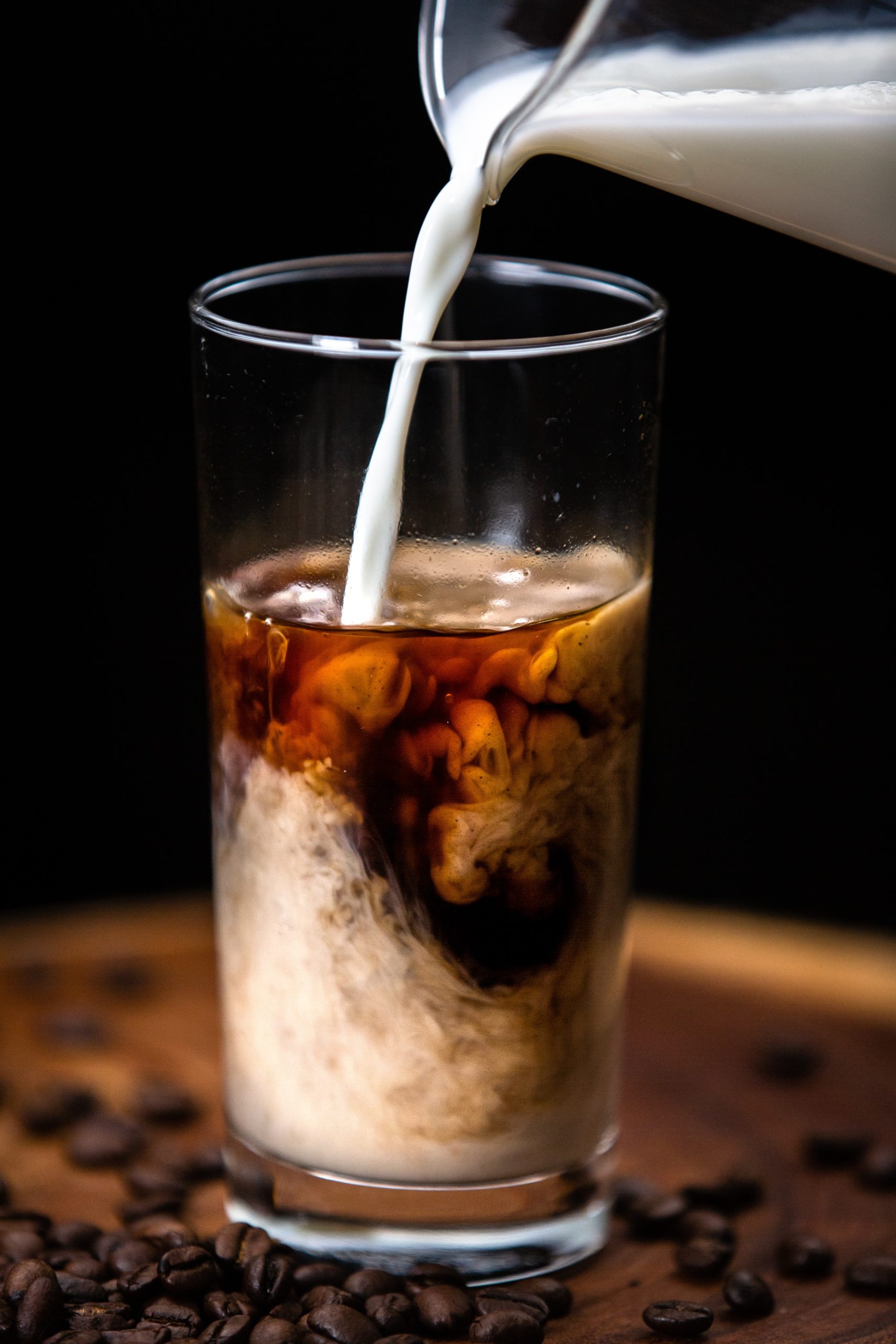 milk being pouring into a glass of cold brew