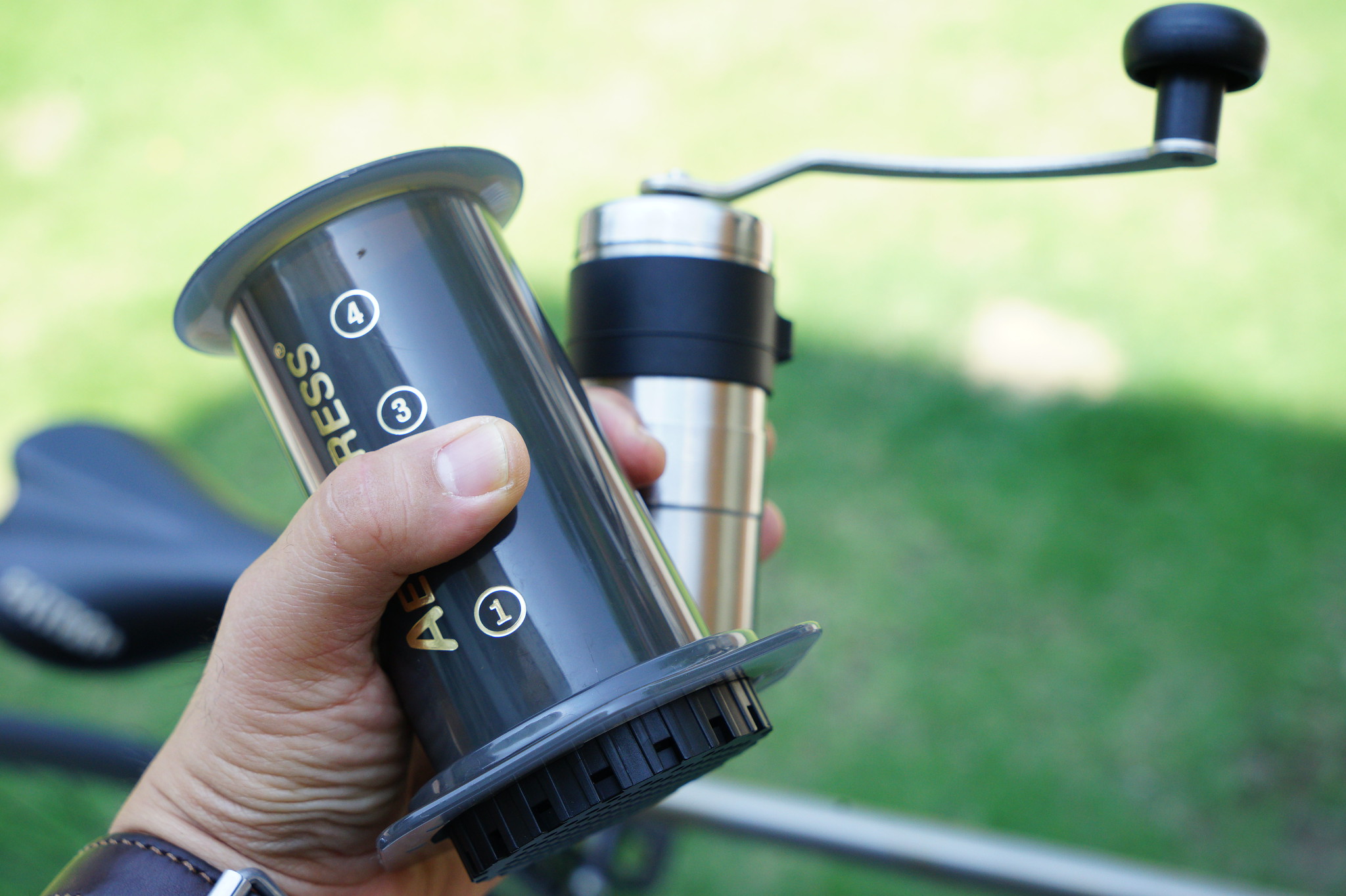 an aeropress and portable coffee grinder held in a hand