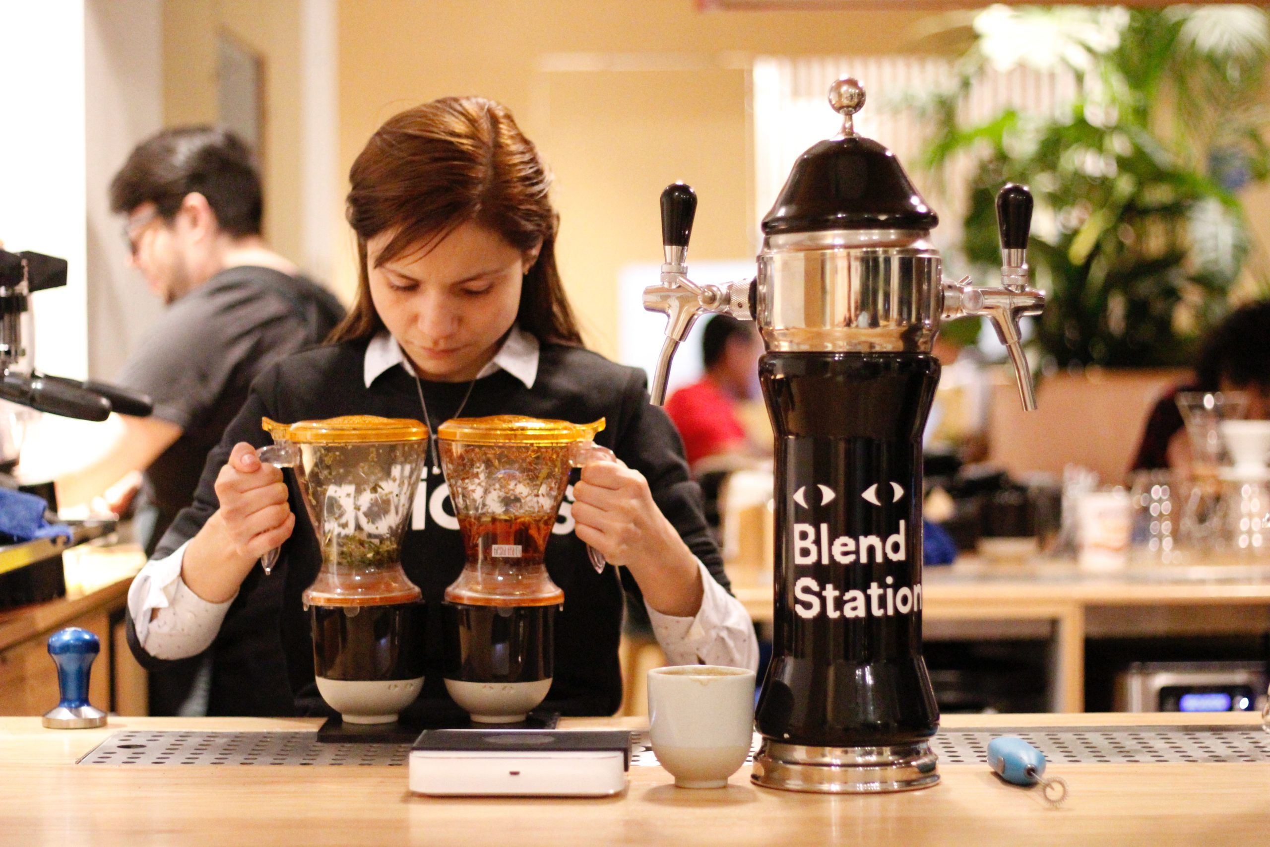 a barista holding two drip coffee